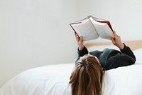 Woman reading a book on her bed during coronavirus quarantine