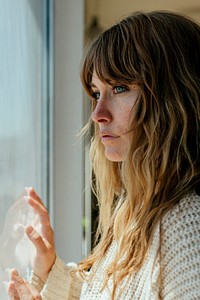 Sad woman staring out the window during a lockdown