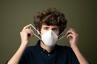 Young Caucasian man putting on a disposable protective mask