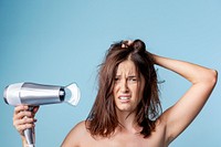 Frustrated woman using a blow dryer 