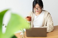 Asian woman drinking coffee while working at home 