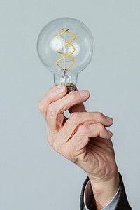 Senior man holding a light bulb against a blue background
