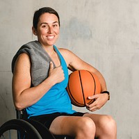 Happy female athlete in a wheelchair with a basketball 