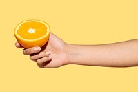 Woman holding half an orange against a yellow background design resource 