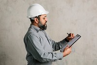 Indian engineer writing on a paper clipboard