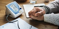 Blood pressure measure machine with senior people holding hands closeup