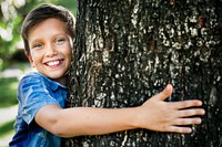 Cheerful boy hugging tree to save environment