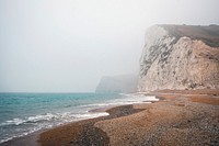 Bluffs line the seashore of a foggy ocean beach. Original public domain image from Wikimedia Commons
