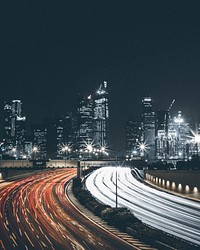 A photo of a lit up city skyline with a light trails from a traffic time lapse. Original public domain image from <a href="https://commons.wikimedia.org/wiki/File:Cityscape_and_traffic_light_trails_(Unsplash).jpg" target="_blank" rel="noopener noreferrer nofollow">Wikimedia Commons</a>