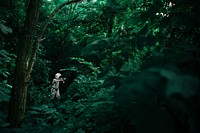 A person dressed in an other-worldly space suit surrounded by verdant forest vegetation on Nun's Island. Original public domain image from Wikimedia Commons