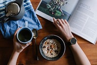 A person reading a book over a cup of coffee and a bowl of granola. Original public domain image from Wikimedia Commons