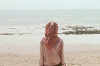 Woman sitting on beach shore in front of sea waves. Original public domain image from Wikimedia Commons