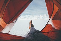 A person in a tent with their feet out the opening camping on a snow covered mountain in Deer Creek Reservation.. Original public domain image from <a href="https://commons.wikimedia.org/wiki/File:Camper_in_deer_creek_reservation_(Unsplash).jpg" target="_blank" rel="noopener noreferrer nofollow">Wikimedia Commons</a>