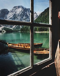 A window view looking at a pair of boats floating in the river with a mix of green and snow covered mountains.. Original public domain image from Wikimedia Commons