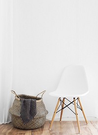 A minimalist shot of a woven laundry basket next to a chair against a white backdrop. Original public domain image from Wikimedia Commons.