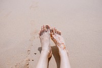 Woman with a henna style tattoo on her foot rests her feet in the sands of El Nido. Original public domain image from Wikimedia Commons