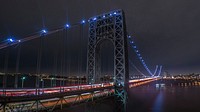 A close-up view of a bridge illuminated with blue lights, taken from the city's skyline. Original public domain image from Wikimedia Commons