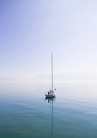 Lone sailboat sitting on a calm blue lake on a sunny day in Lausanne. Original public domain image from Wikimedia Commons