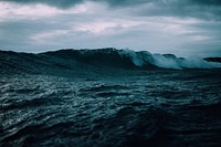 A wave rolling on a turbulent sea, beneath a moody cloudy sky at Omaha. Original public domain image from Wikimedia Commons