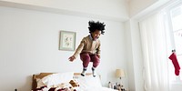 Young happy kid having fun jumping up and down on a bed social banner