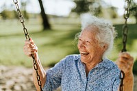 Cheerful senior woman on a swing at a playground