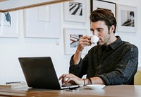 Man sipping a coffee while working