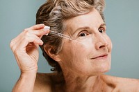 Senior woman applying moisturizer on her eye wrinkles