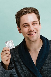 Portrait of a blond man showing a latex condom