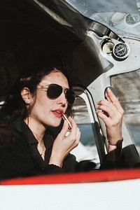 Airwoman applying red lipstick in the cockpit