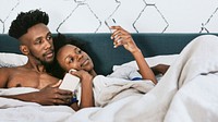 Black couple watching a video on a phone in bed