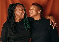 Happy lesbian couple standing by a red background