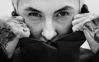 Tattooed woman covering her face with a black hoodie