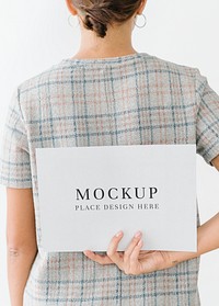 Woman in a gray plaid dress showing a blank card mockup on her back