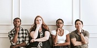 Diverse grumpy people sitting by a white wall