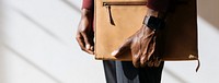 Man with a wristwatch holding a brown briefcase