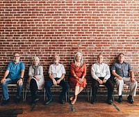 Diverse elderly people sitting in a row against a brick wall background