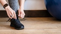 Active woman wearing a smartwatch tying her shoelaces