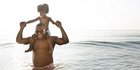 African American dad and son playing piggyback in the sea text space banner 