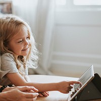 Blonde girl playing on a digital tablet