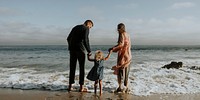 Parents holding daughter's hand at the beach