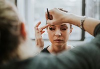 Makeup artist applying eyeshadow onto model