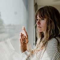 Sad woman staring out the window during a lockdown