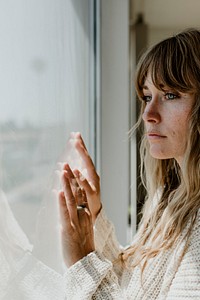 Sad woman staring out the window during a lockdown