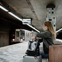 Woman looking at her watch while waiting for the train during the coronavirus pandemic 