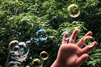 Soap bubbles in the park with kid&rsquo;s hand closeup