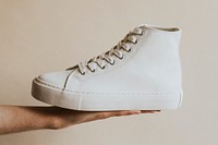 Hand holding white high top sneakers