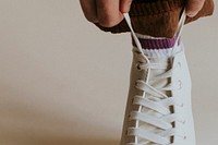 Man fixing shoelaces white high top sneaker