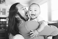 Cheerful Asian American father hugging his little son