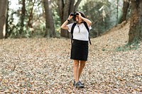 Active retired woman using binoculars to see the beauty of nature