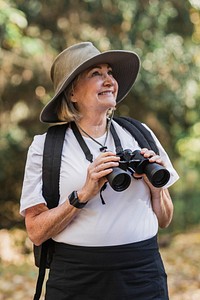 Active old woman using binoculars to see the beauty of nature